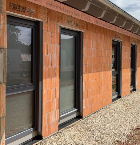 Fassade eines Gebäudes mit orangefarbenen Ziegeln und großen Fenstern.