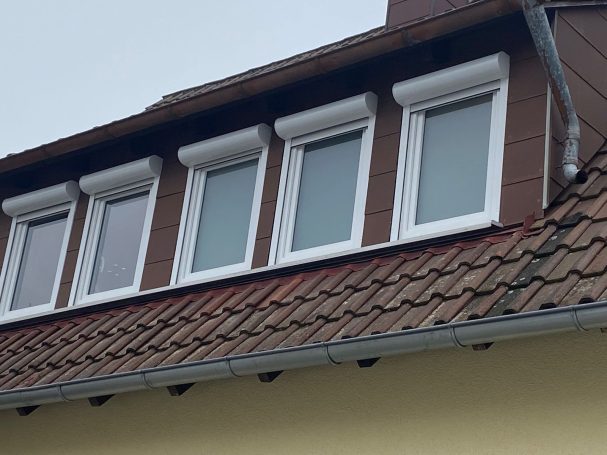 Dach mit Fenstern und brauner Schindelfassade.