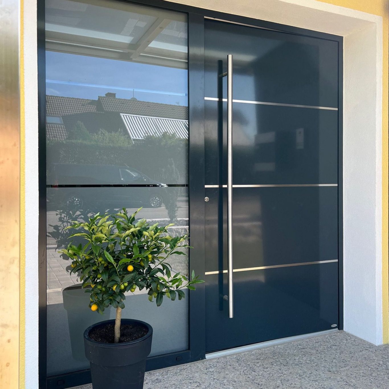 Moderne Haustür in Dunkelgrau mit Glas und silbernem Türgriff.