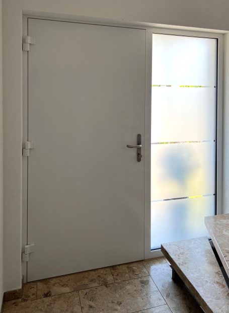 Weiße Tür mit Glaseinsatz und braunem Bodenbelag.