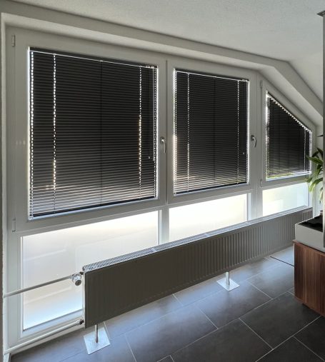 Große Fenster mit Rollläden und einer Heizungsabdeckung in einem modernen Raum.